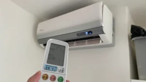 2026 租屋冷氣省電實測：在外宿套房中手持冷氣遙控器調整合適溫度，搭配防西曬隔熱裝備與空氣對流工作流，展現小資族降低夏季高昂電費的省錢黑客生活場景。